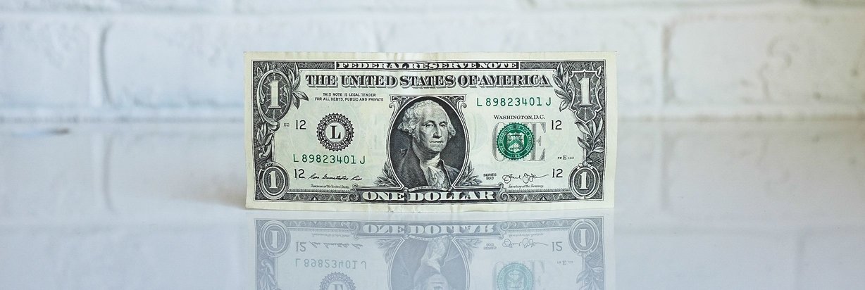 One dollar bill with a brick white wall background